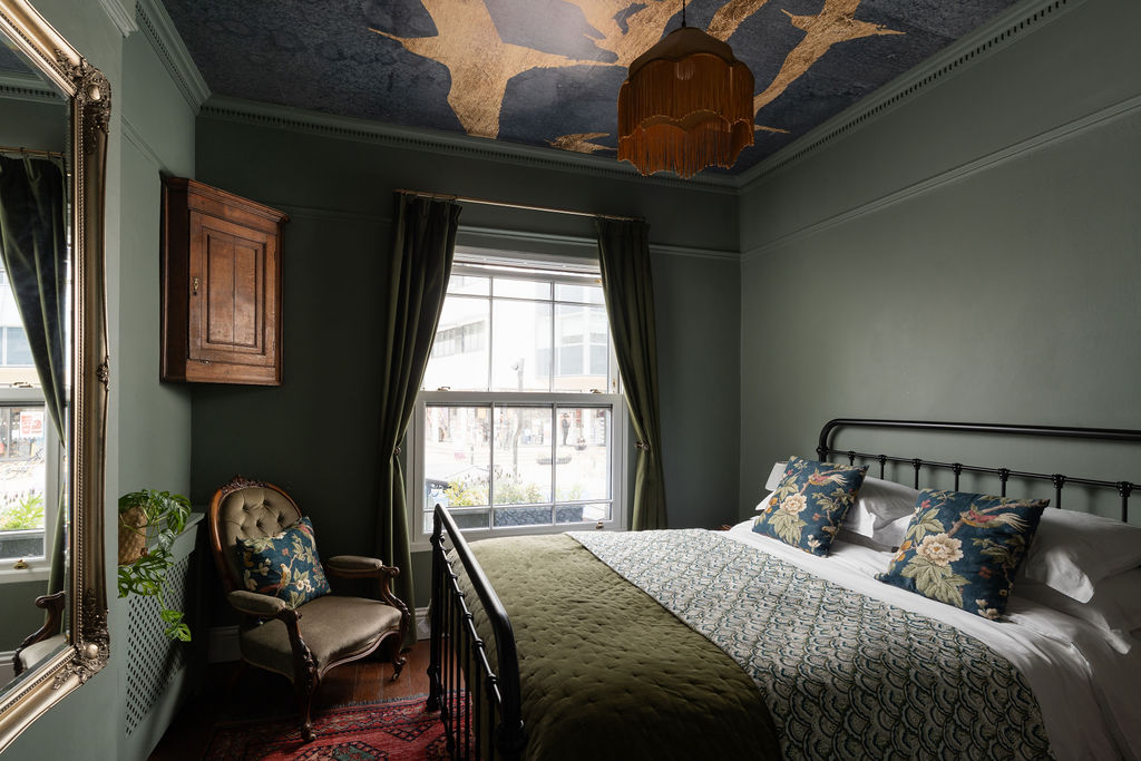 Doghouse Inn bedroom with green walls and sea-view window