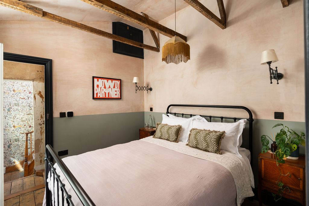 Doghouse Inn room with exposed beams and iron bed